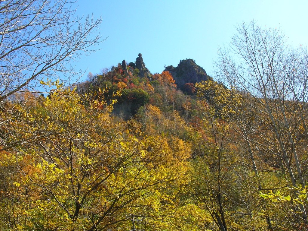 Autumn colour in Sounkyo Gorge, with red and yellow trees below grey cliffs