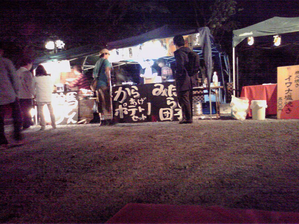 Night food stalls with signs for karaage and mitarashi dango