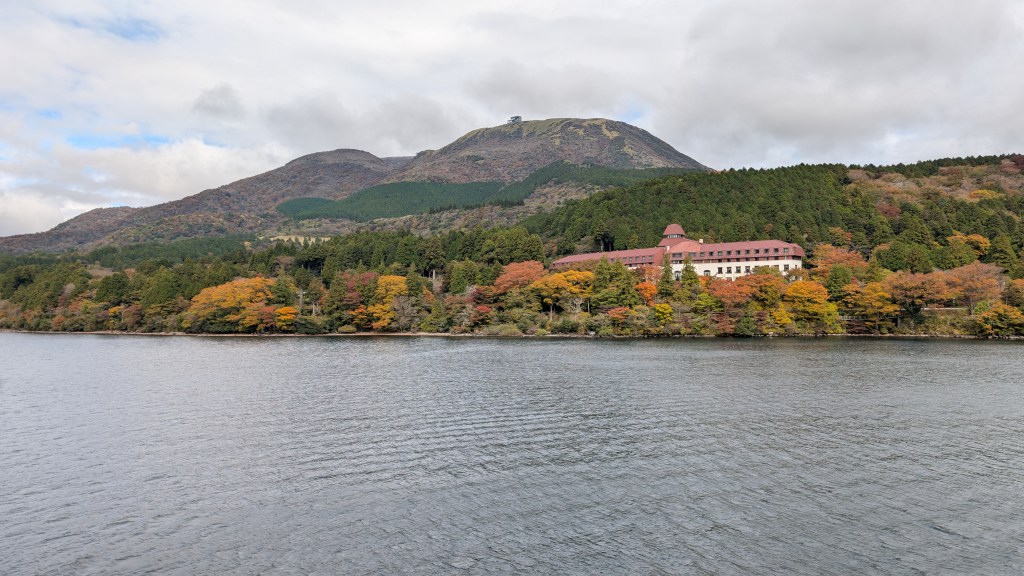 Lake Ashi with autumn hillside color and a red-roofed building in Hakone
