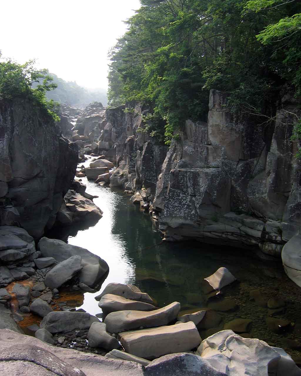A flat-bottomed boat on the Satetsu River between high cliffs at Geibikei Gorge, Iwate, Japan