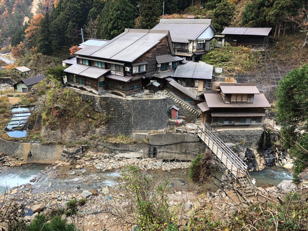 Wooden Korakukan inn at Jigokudani Onsen surrounded by autumn trees