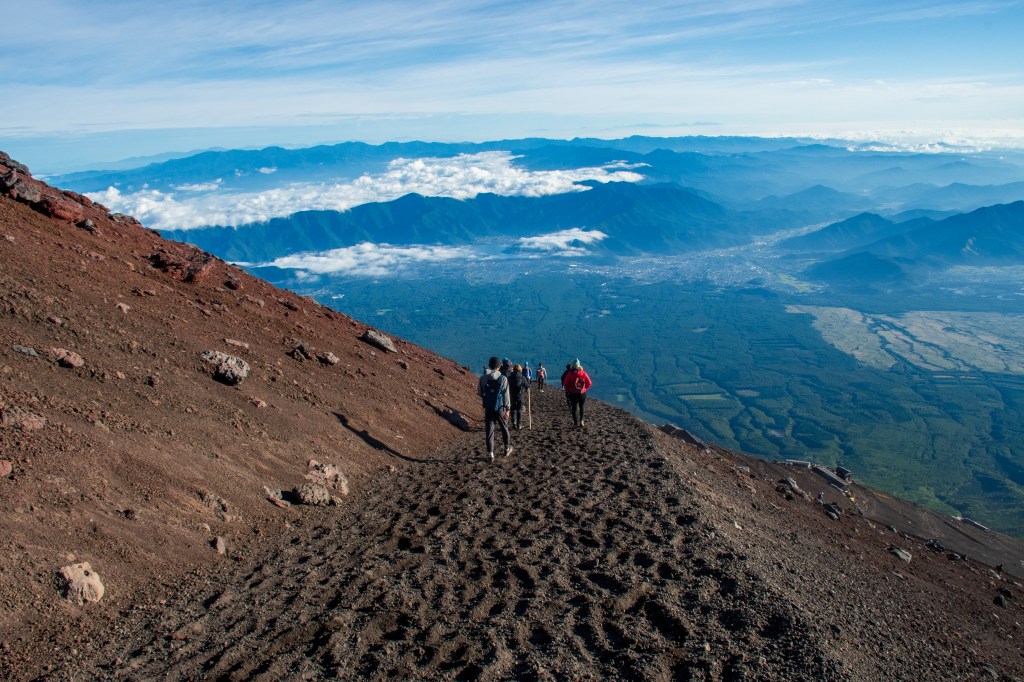 A rocky section of the Yoshida Trail on Mount Fuji with climbers above the treeline