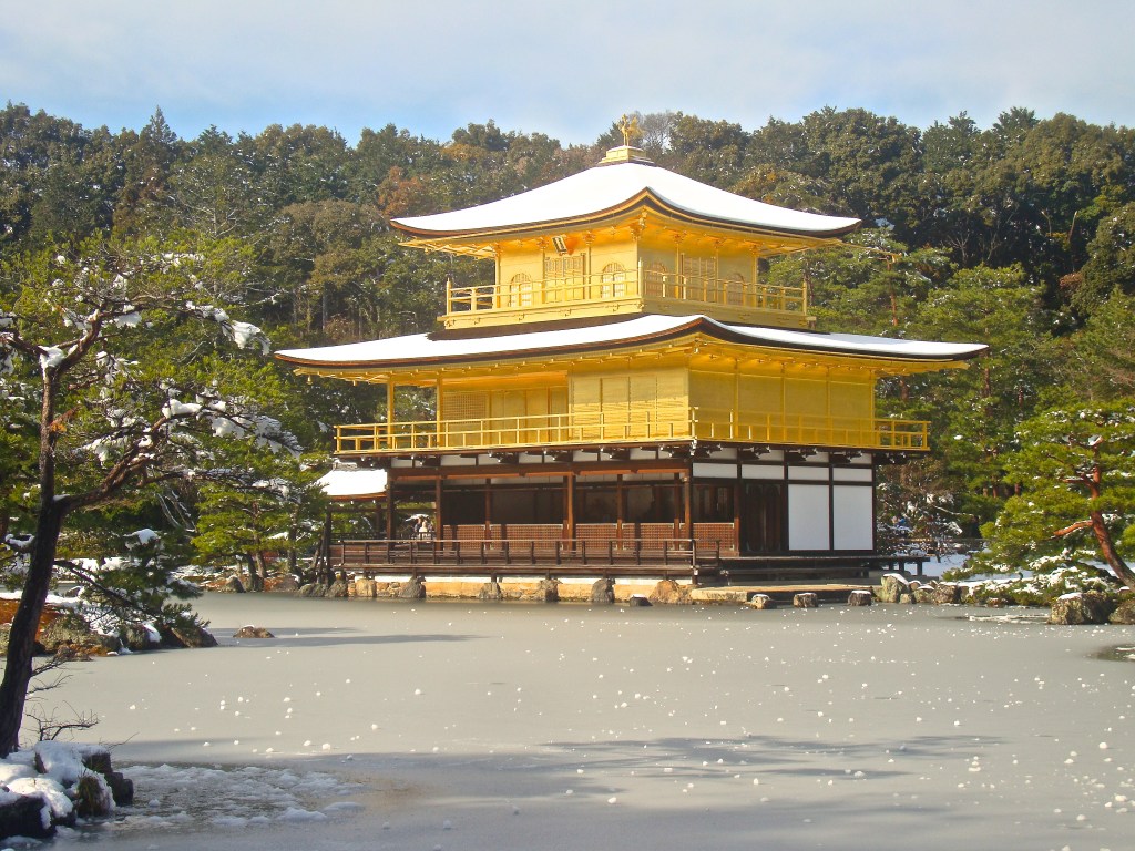 Kinkaku-ji covered in snow with the frozen pond in front