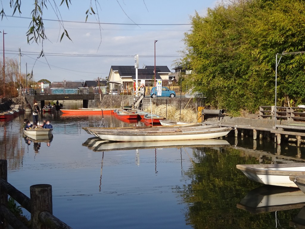 A wooden donko boat poled along a quiet canal in Yanagawa, with houses on the bank